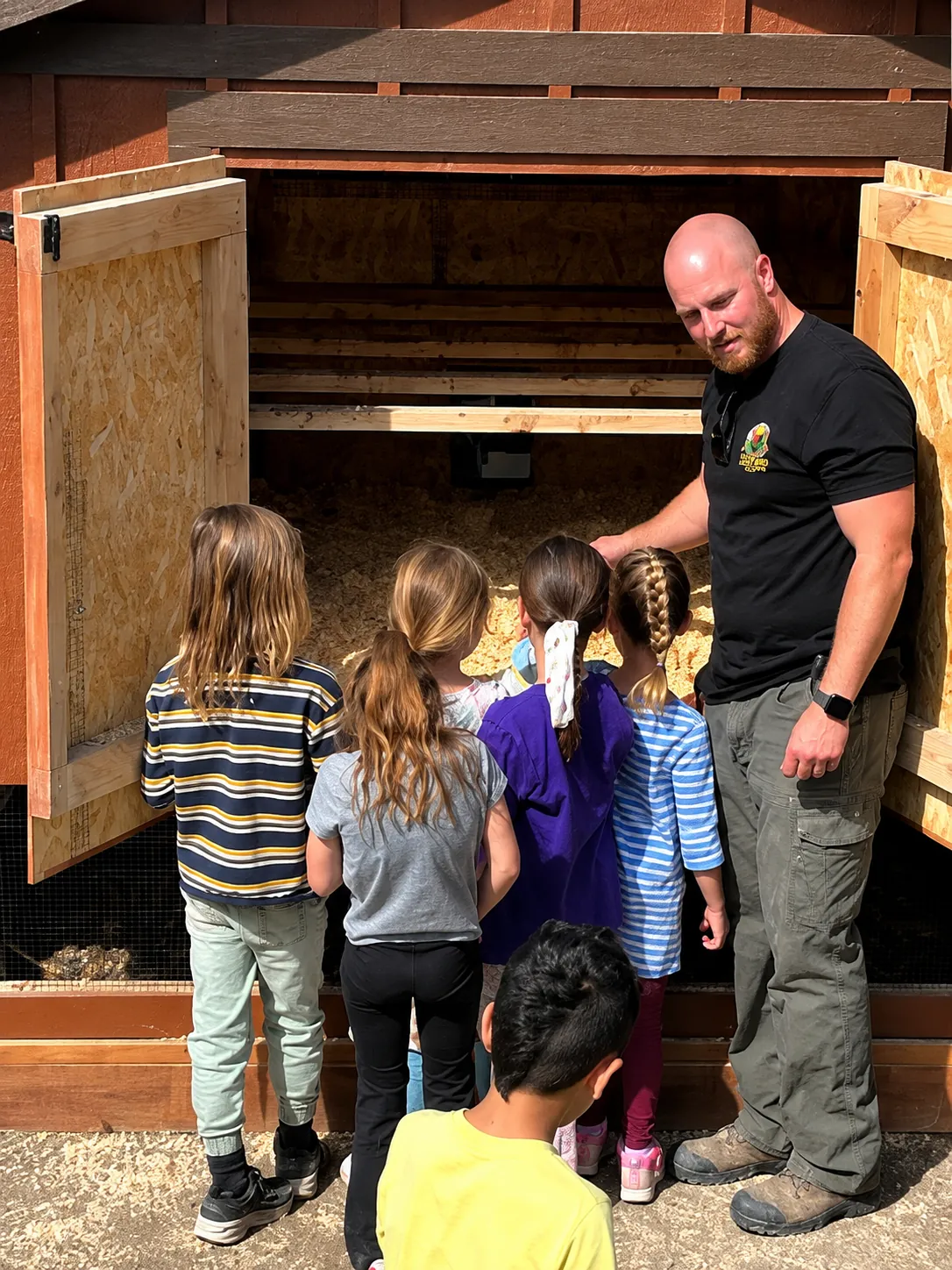 First graders looking inside a coop's nesting and roost area with Austin
