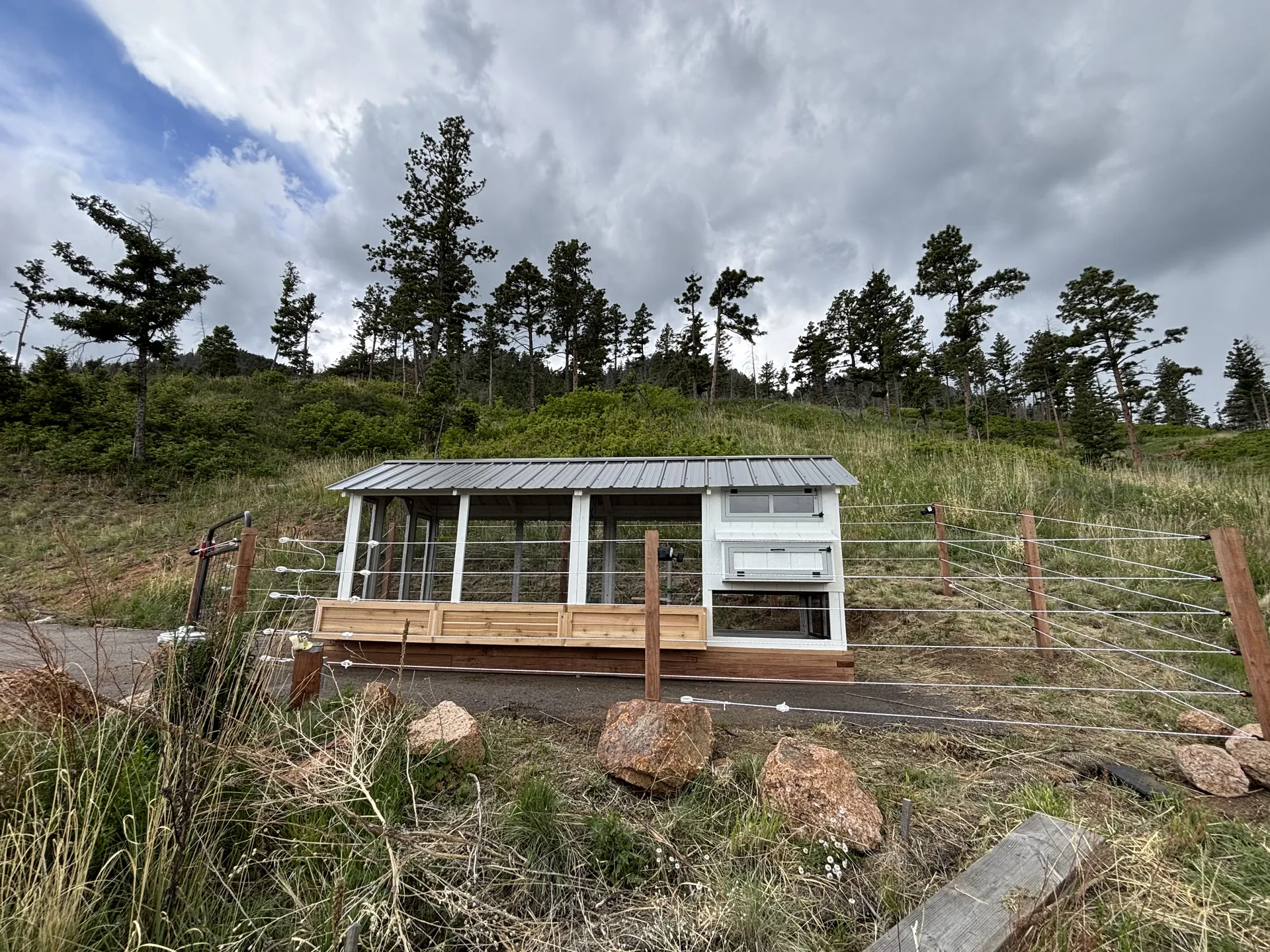 Side view of the fortified Barn House Coop with planter boxes and electric fence strands